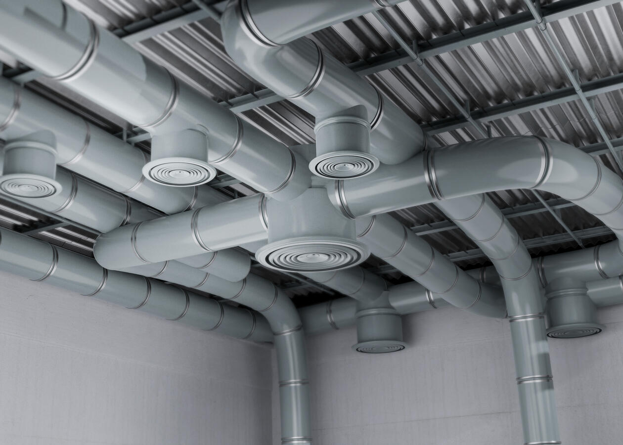 Round ventilation ducts and ceiling diffusers beneath a metal roof.