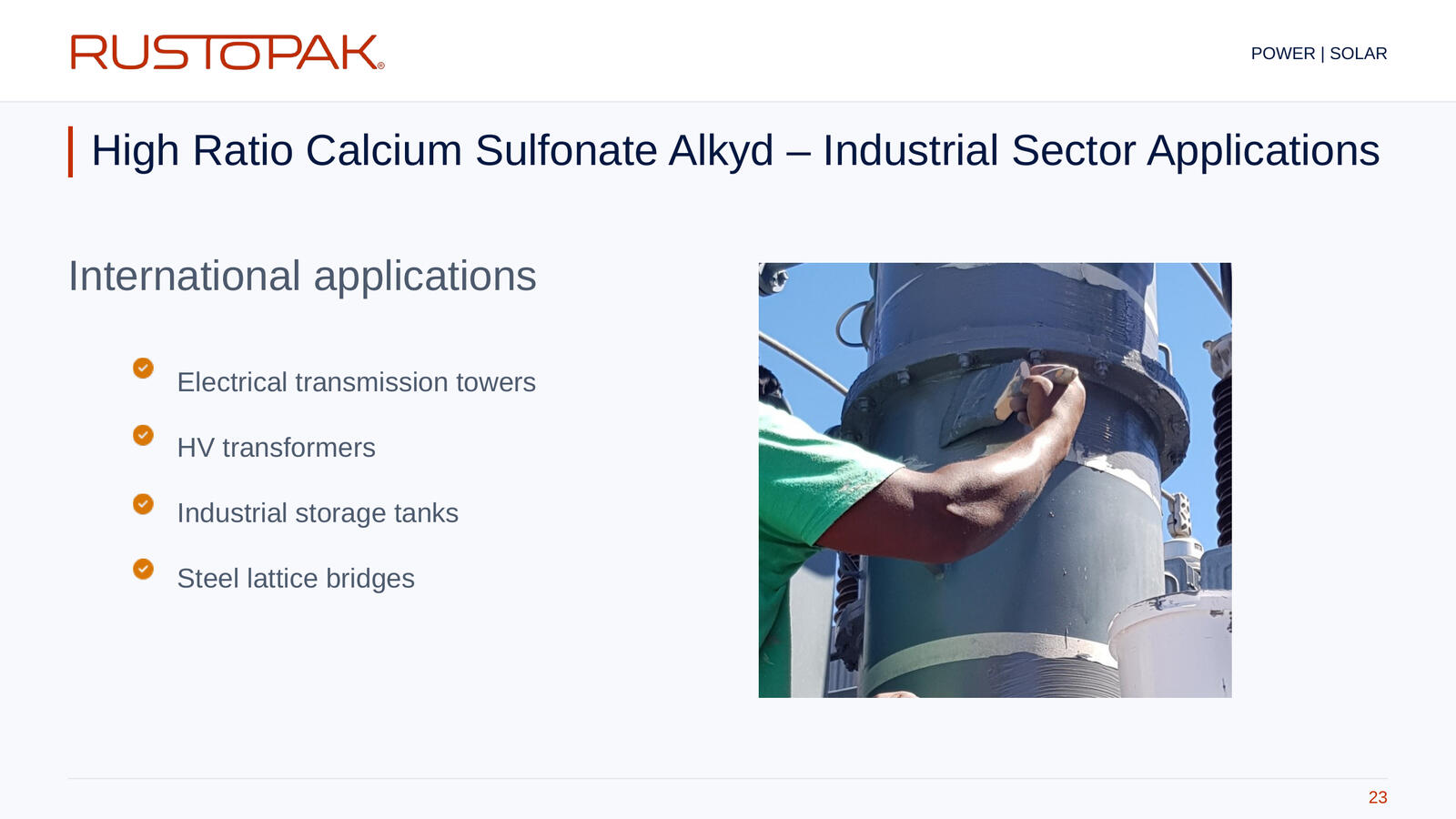 Slide 23: Industrial application list beside a photograph of a worker applying coating by brush to cylindrical steel equipment.